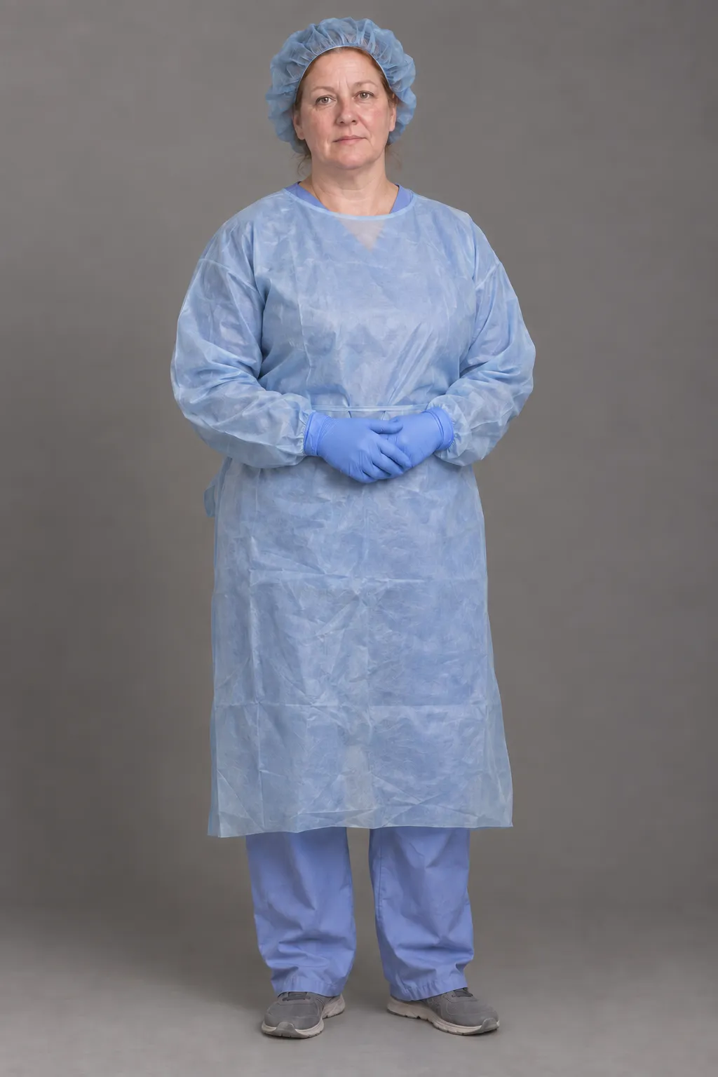 Full-length reference of the nurse in blue surgical clothing and gloves.