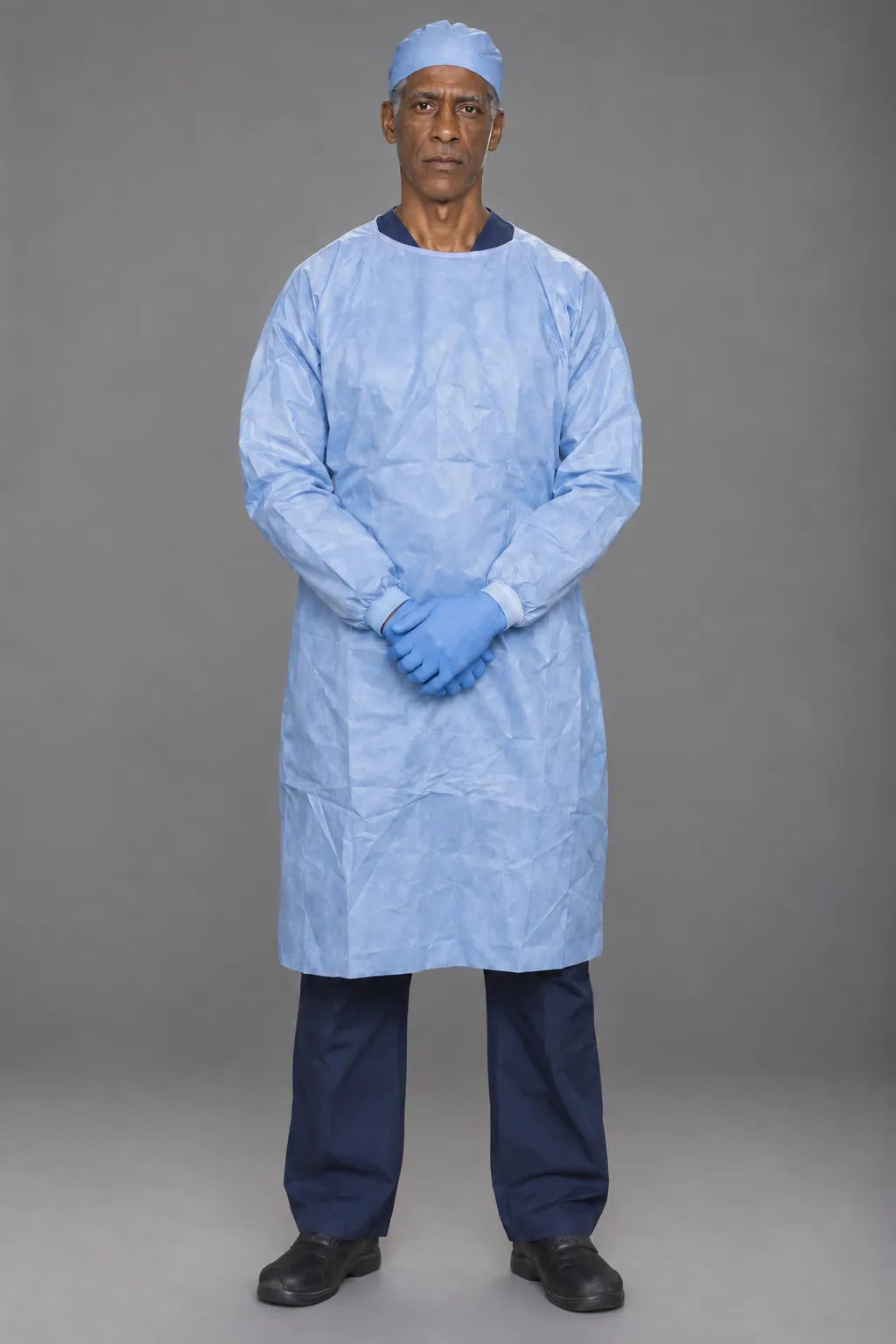 Full-length reference of the surgeon in a blue gown, cap, and gloves.